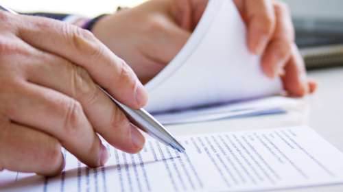 Hands of Business man in dark suit writing in his datebook